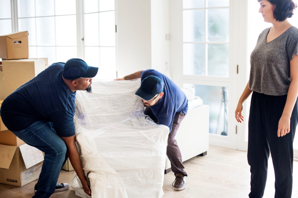 Man and van crew lifting a chair wrapped in cling film on a moving day
